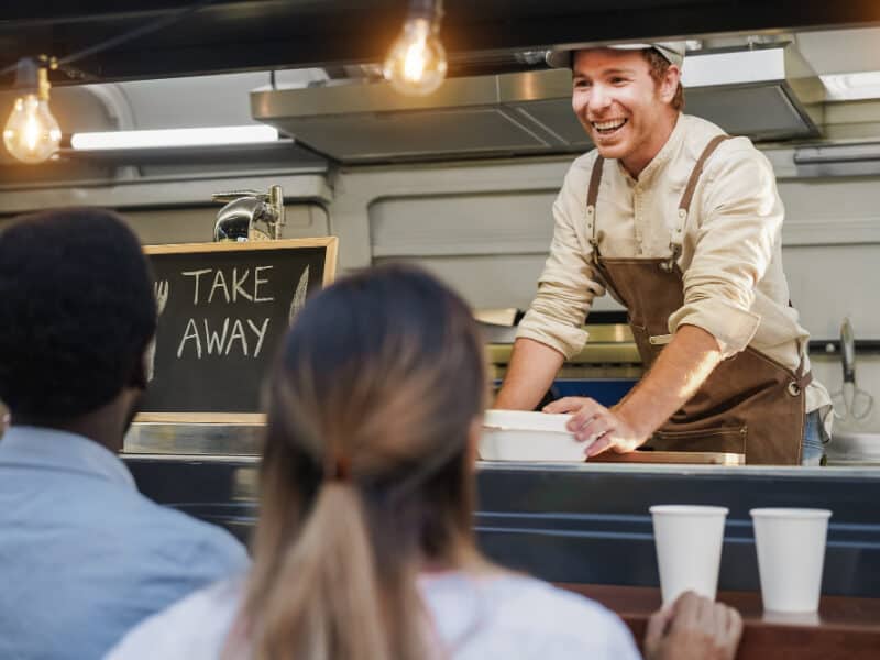 hispanischer-mann-serviert-essen-zum-mitnehmen-im-food-truck-fokus-auf-das-gesicht-des-kochs hispanischer-mann-serviert-essen-zum-mitnehmen-im-food-truck-fokus-auf-das-gesicht-des-kochs