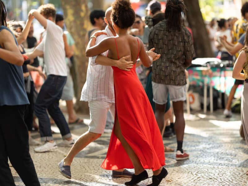 paare-tanzen-auf-der-strasse-gebraeunte-frau-in-rotem-leuchtendem-kleid-in-der-mitte paare-tanzen-auf-der-strasse-gebraeunte-frau-in-rotem-leuchtendem-kleid-in-der-mitte